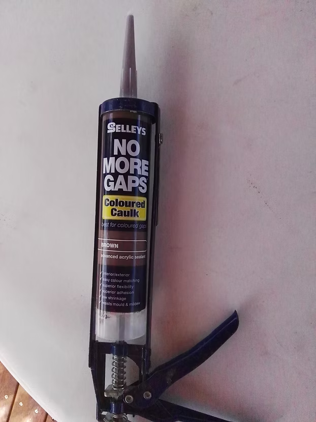 Brown acrylic caulk in a caulking gun ready for post repairs
