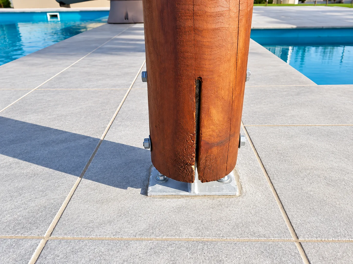 Close-up of a split in a round timber post at its metal bracket