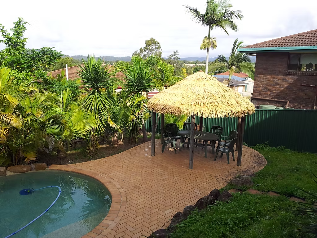 Synthetic Bali thatch gazebo shading a dining area beside a swimming pool